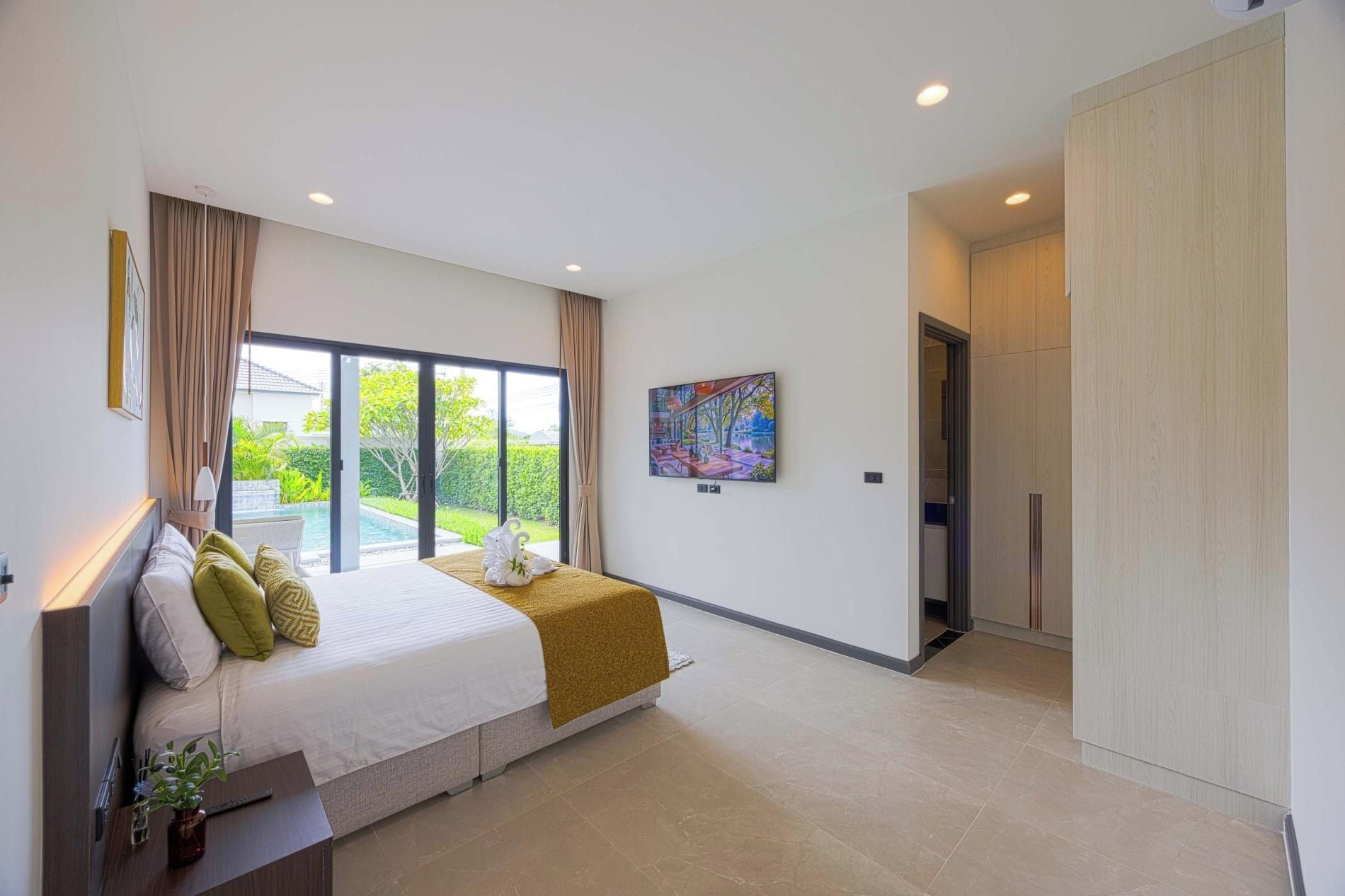Un dormitorio moderno con una cama grande, un cuadro y vistas a una piscina.