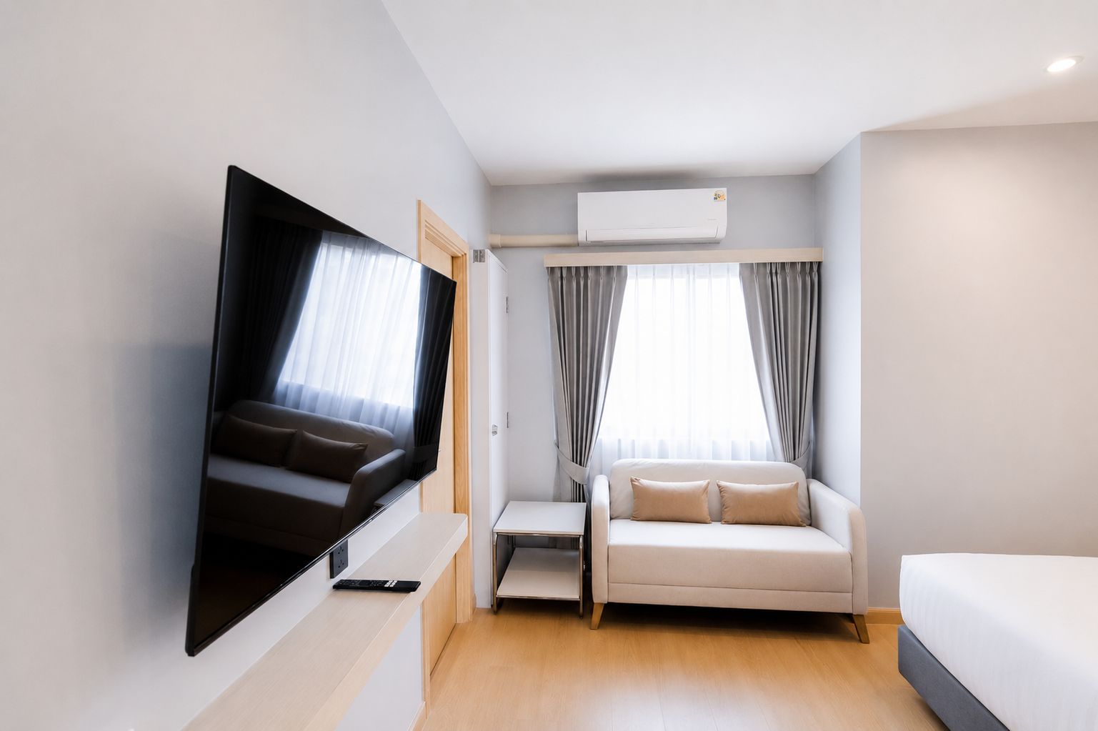 Una camera d'albergo moderna con TV a schermo piatto, divano, letto e finestra con tende.