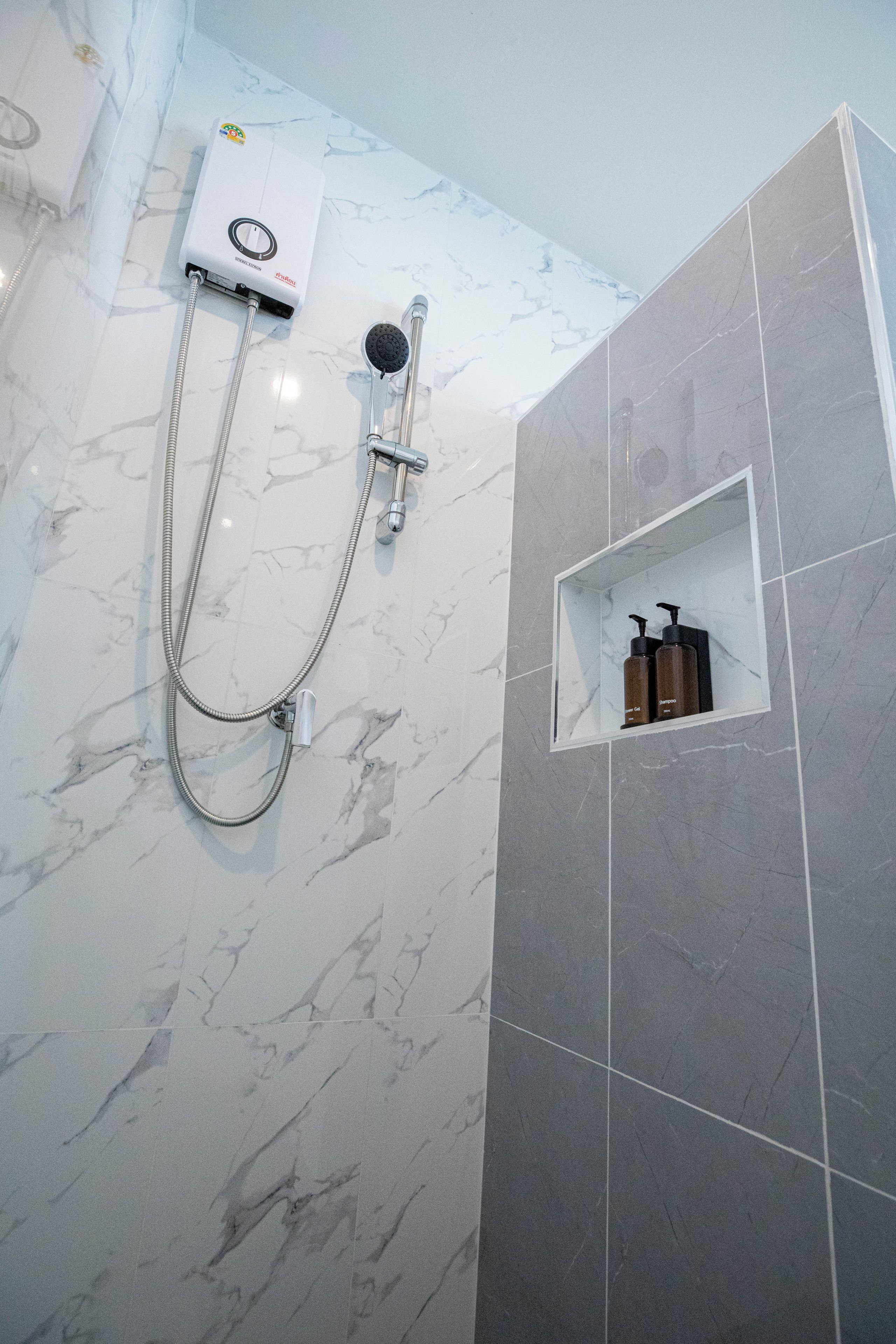 Un baño con ducha, inodoro y repisa con artículos de aseo.