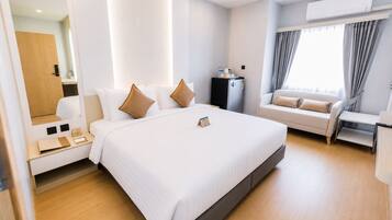 Una habitación de hotel moderna con una cama grande, un sofá, un escritorio y un equipo de aire acondicionado.
