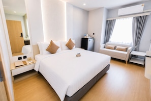 Una habitación de hotel moderna con una cama grande, un sofá, un escritorio y un equipo de aire acondicionado.