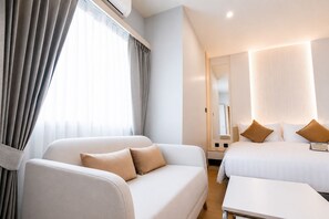 A hotel room with a sofa, a bed, a bedside table, and a mirror. - 42C Lite Hotel (Mueang Nakhon Sawan)
