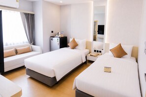 A hotel room with two beds, a desk, a minibar, and a large window with curtains. - 42C Lite Hotel (Mueang Nakhon Sawan)