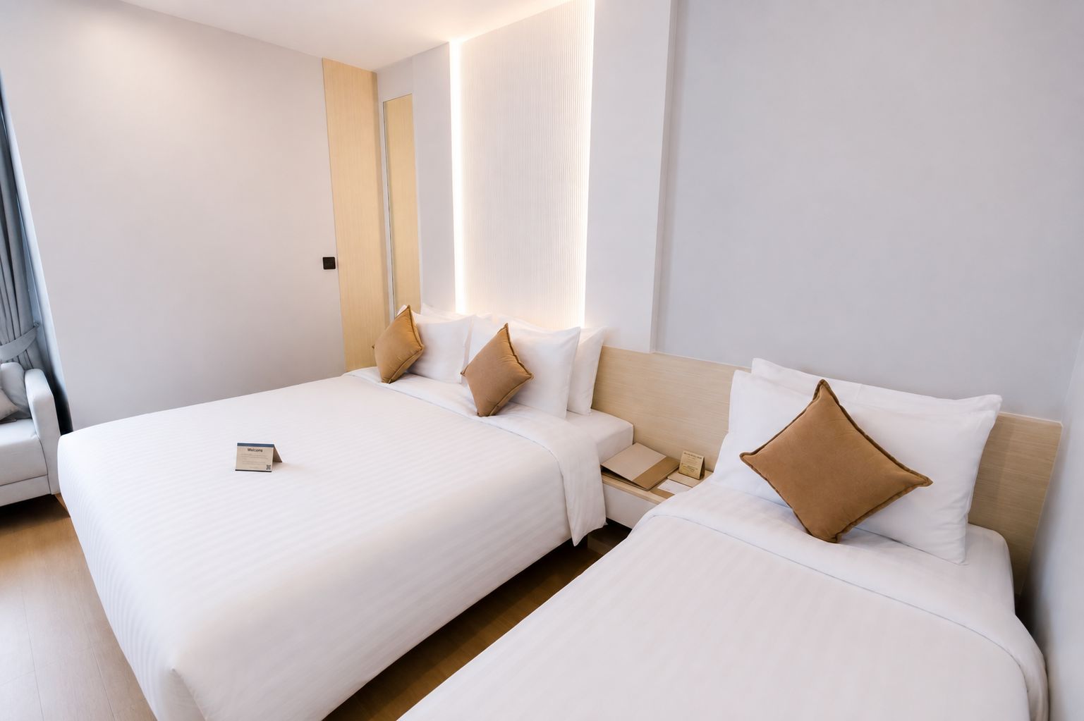 Una camera d'albergo con due letti, un comodino, una sedia e uno specchio grande.