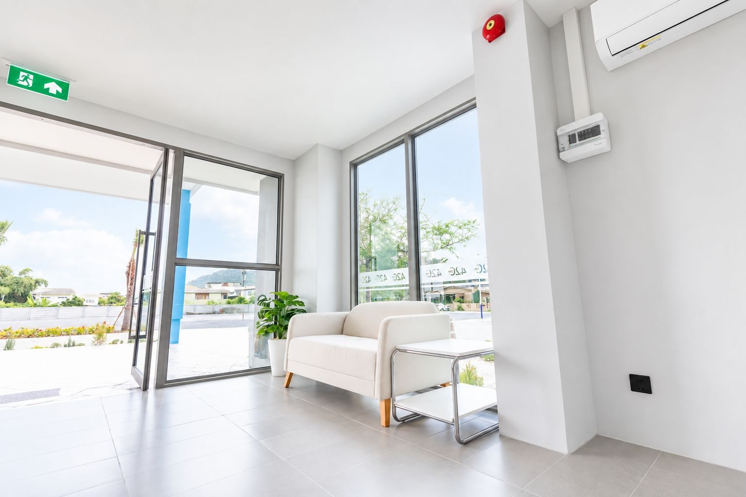 Un interior moderno con un sofá blanco, ventanas amplias y una señal de salida.