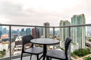 A balcony with a round table and two chairs, overlooking a cityscape with high-rise buildings. - Blueground | Fulton River District, gym, nr Park (Chicago)