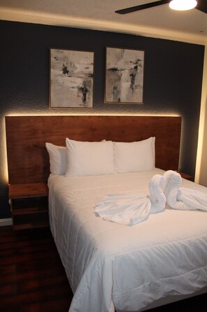 Ein Hotelzimmer mit einem großen Bett, weißer Bettwäsche und zwei abstrakten Bildern an der Wand.