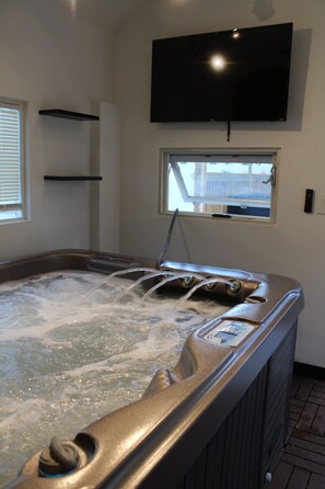 Ein Whirlpool mit Wasserstrahlen, einem angebrachten Fernseher und einem Fenster mit Aussicht.
