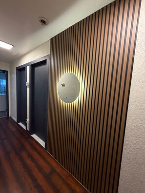 A hallway with wooden paneling, a round mirror, and a door. - Luxury 8BR HOME + Private Basement Apartment, Pool, Jacuzzi, Sauna & Gym (Las Vegas)