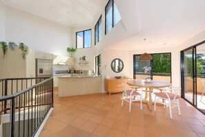 Eine moderne Küche mit Essbereich, großen Fenstern und einem Balkon.