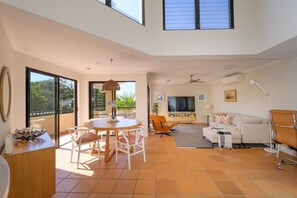 A spacious living area with a dining table, sofas, and a TV. - Pearl in Peregian Beach (Peregian Beach)