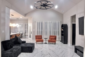 A modern living room with a sectional sofa, two armchairs, a small side table, a built-in TV, and a ceiling fan. - Spacious New 4-bedroom light-house in perfect Dallas with Resort style living. (Dallas)