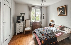 A bedroom with a bed, a chair, a dresser, a television, a window with curtains, a lamp, and a framed picture on the wall. - 4 bedroom cozy home in Royan (Royan)