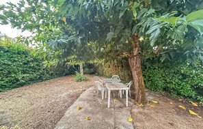 A garden area with a table and chairs under a tree, surrounded by dense foliage. - 4 bedroom cozy home in Royan (Royan)