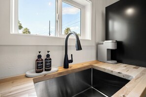 A modern kitchen with a black faucet, a coffee machine, and two bottles of soap on a white countertop. - The Desert Peach | Near ASU, Old Town + Sky Harbor (Tempe)