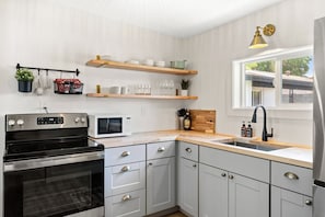 A modern kitchen with a built-in oven, microwave, and stainless steel sink. - The Desert Peach | Near ASU, Old Town + Sky Harbor (Tempe)
