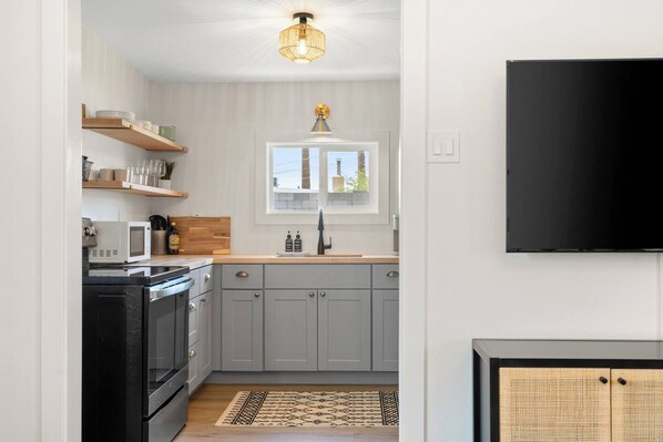 A modern kitchen with grey cabinets, a black stove, and a wooden countertop.