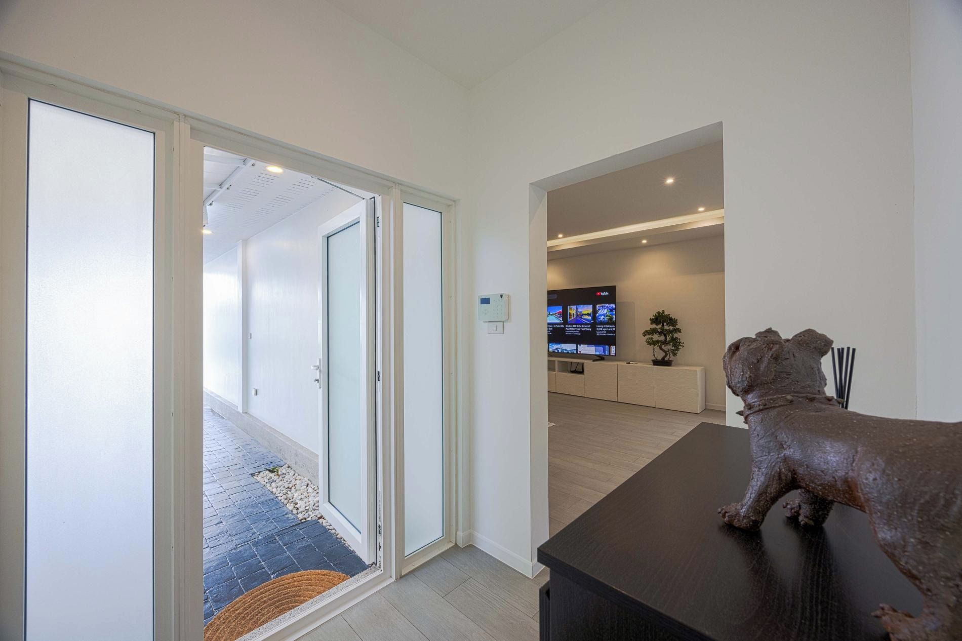 Een moderne woonkamer met een donker houten salontafel, een beeldhouwwerk en een televisie waarop nieuws te zien is.