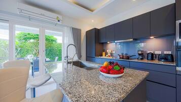 A modern kitchen with a granite countertop, dark cabinetry, and a bowl of fruit.