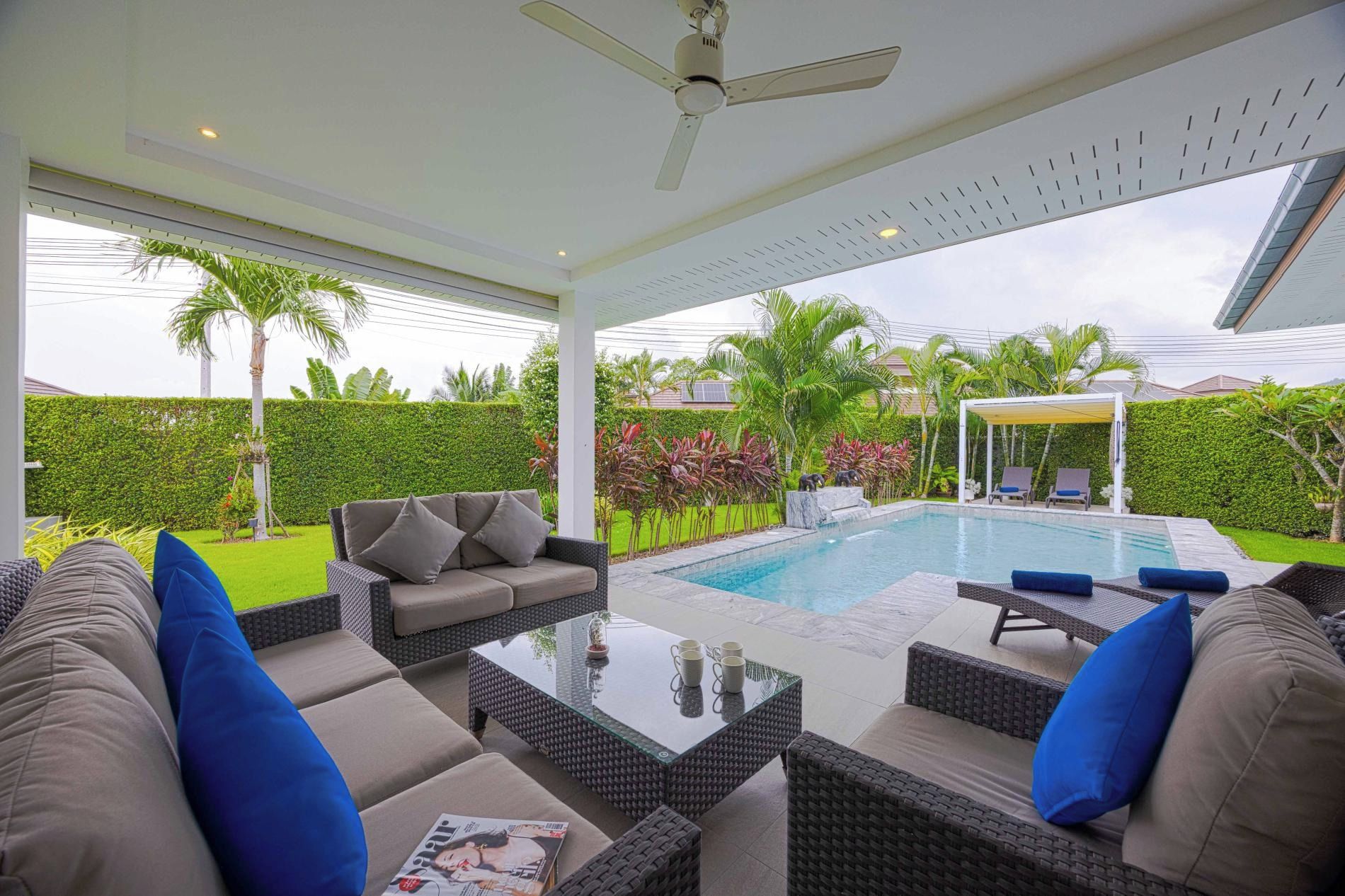 An outdoor living area with a pool, seating, and a covered patio.