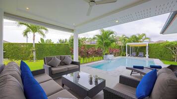 An outdoor living area with a pool, seating, and a covered patio.