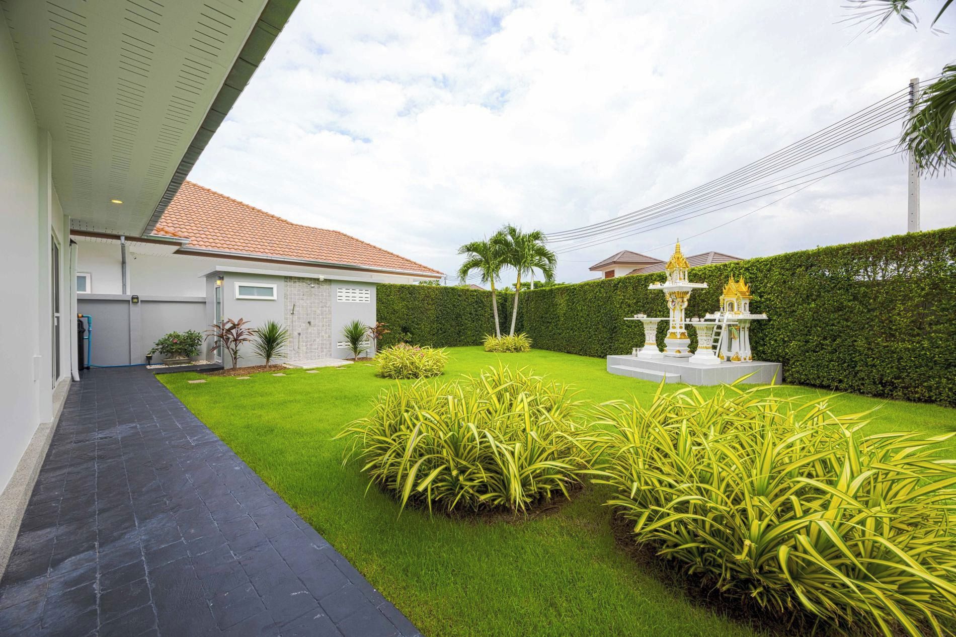 A residential property with a paved driveway, a well-maintained lawn, and a decorative fountain.
