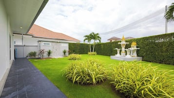 A residential property with a paved driveway, a well-maintained lawn, and a decorative fountain.