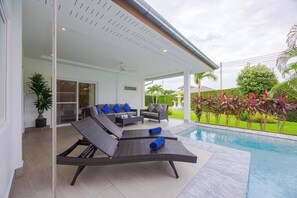 A covered outdoor area with a pool, lounge chairs, and a dining set. - New Private Luxury Pool Villa (ML132) (Hua Hin)