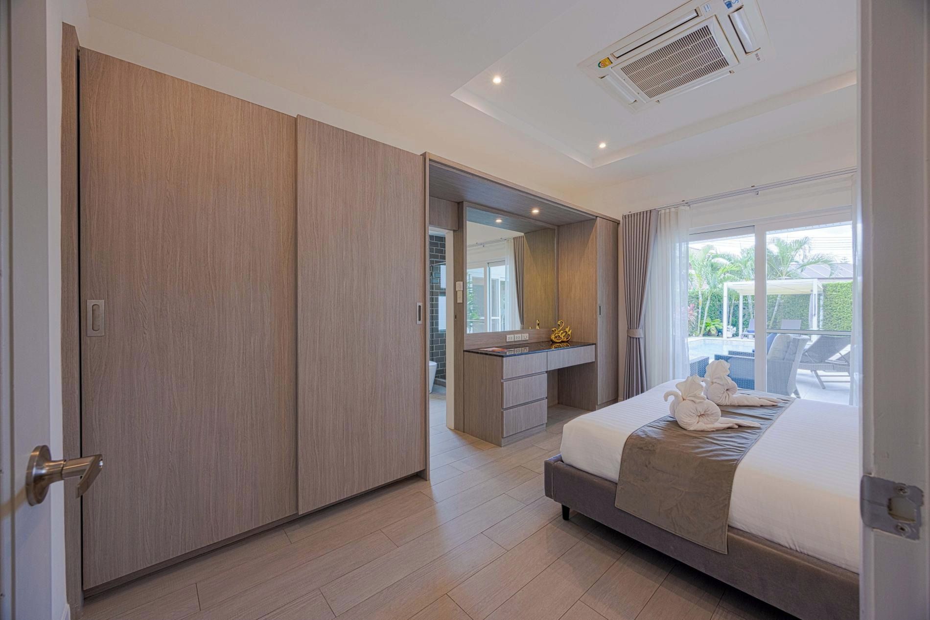 Un dormitorio moderno con una cama grande, un vestidor, un tocador con espejo y vistas al exterior.