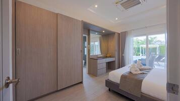 Un dormitorio moderno con una cama grande, un vestidor, un tocador con espejo y vistas al exterior.