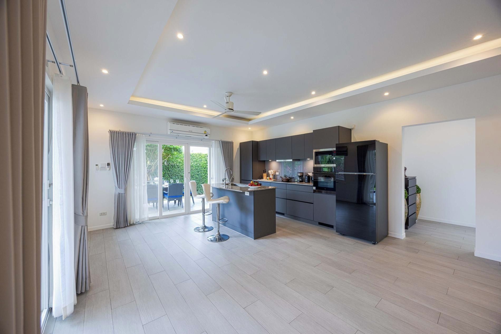 A modern kitchen with a central island, built-in appliances, and a sliding glass door leading to a patio.