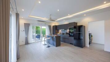 A modern kitchen with a central island, built-in appliances, and a sliding glass door leading to a patio.