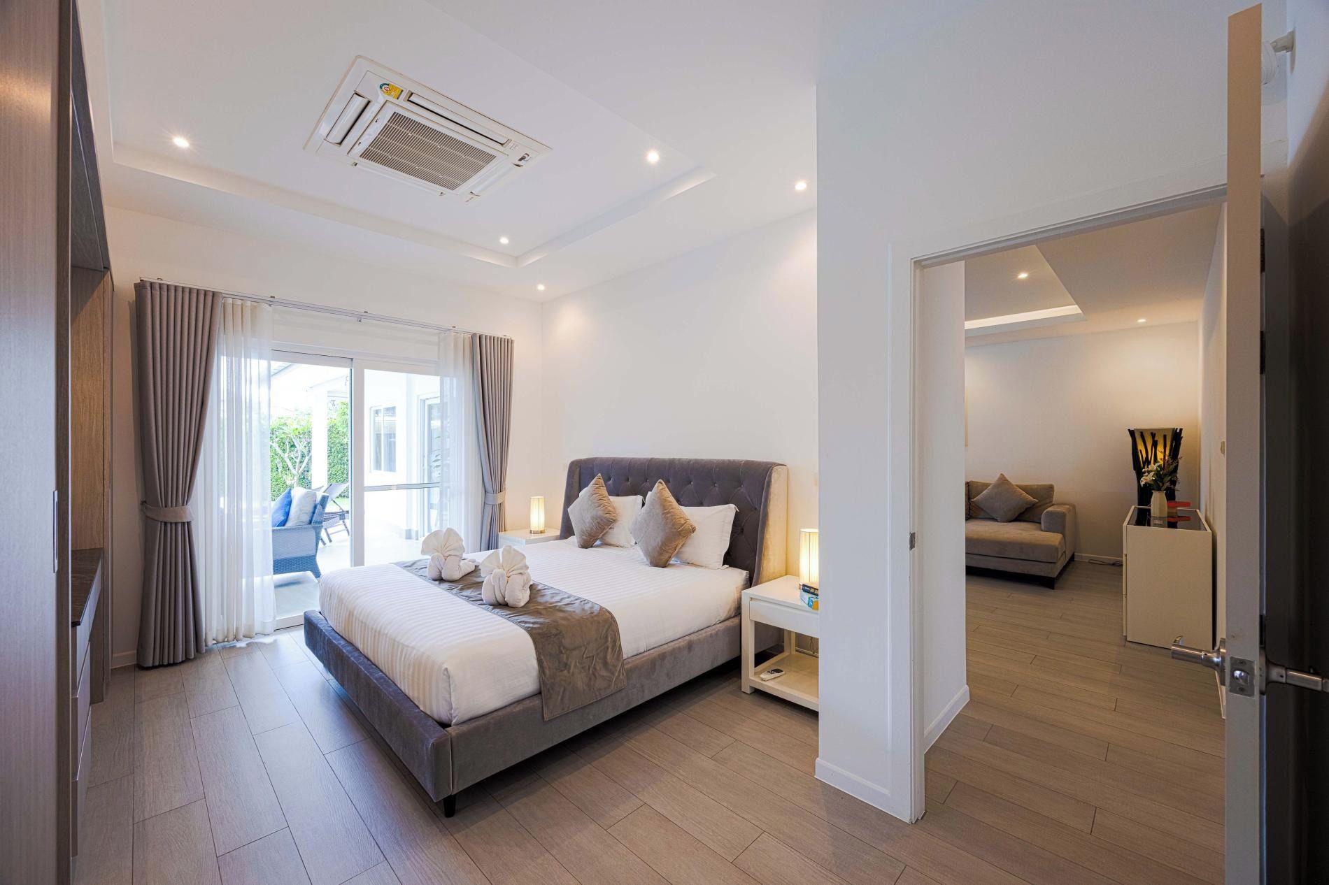 A modern bedroom with a large bed, a bedside table, and a view of a balcony.
