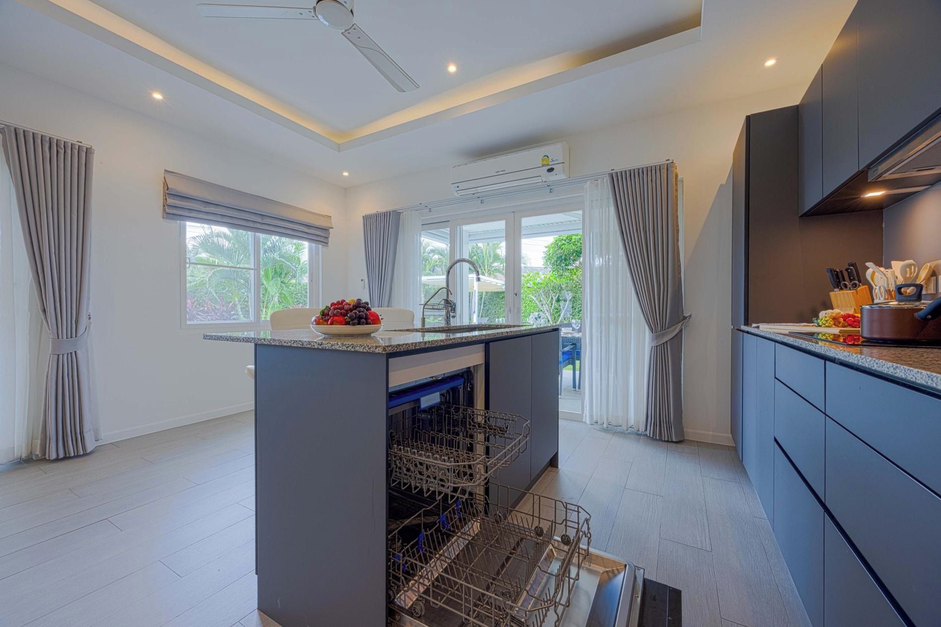 A modern kitchen with a central island, built-in dishwasher, and a view of the outdoors.