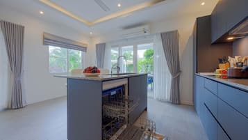 A modern kitchen with a central island, built-in dishwasher, and a view of the outdoors.