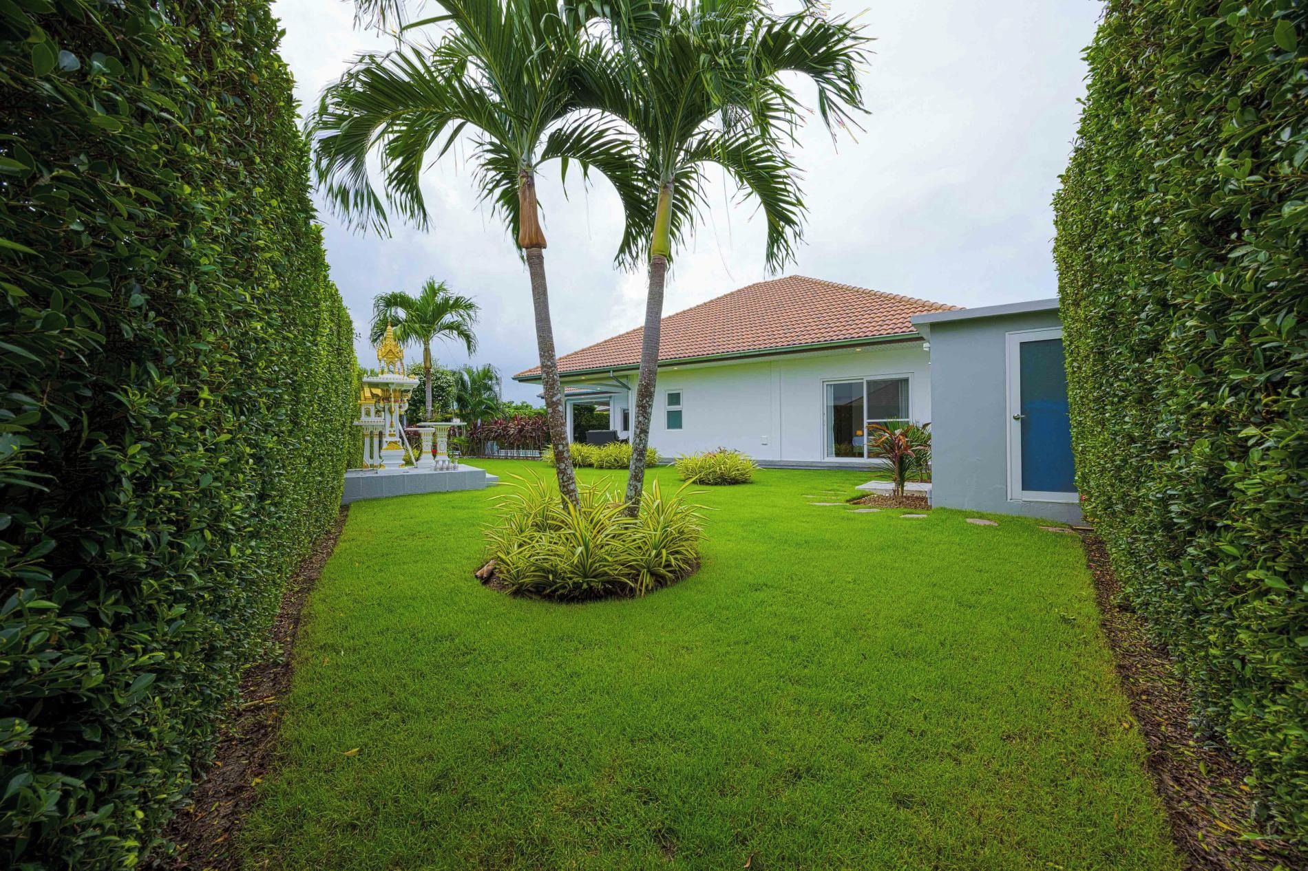 A modern building with a tiled roof, surrounded by well-maintained grass and palm trees.
