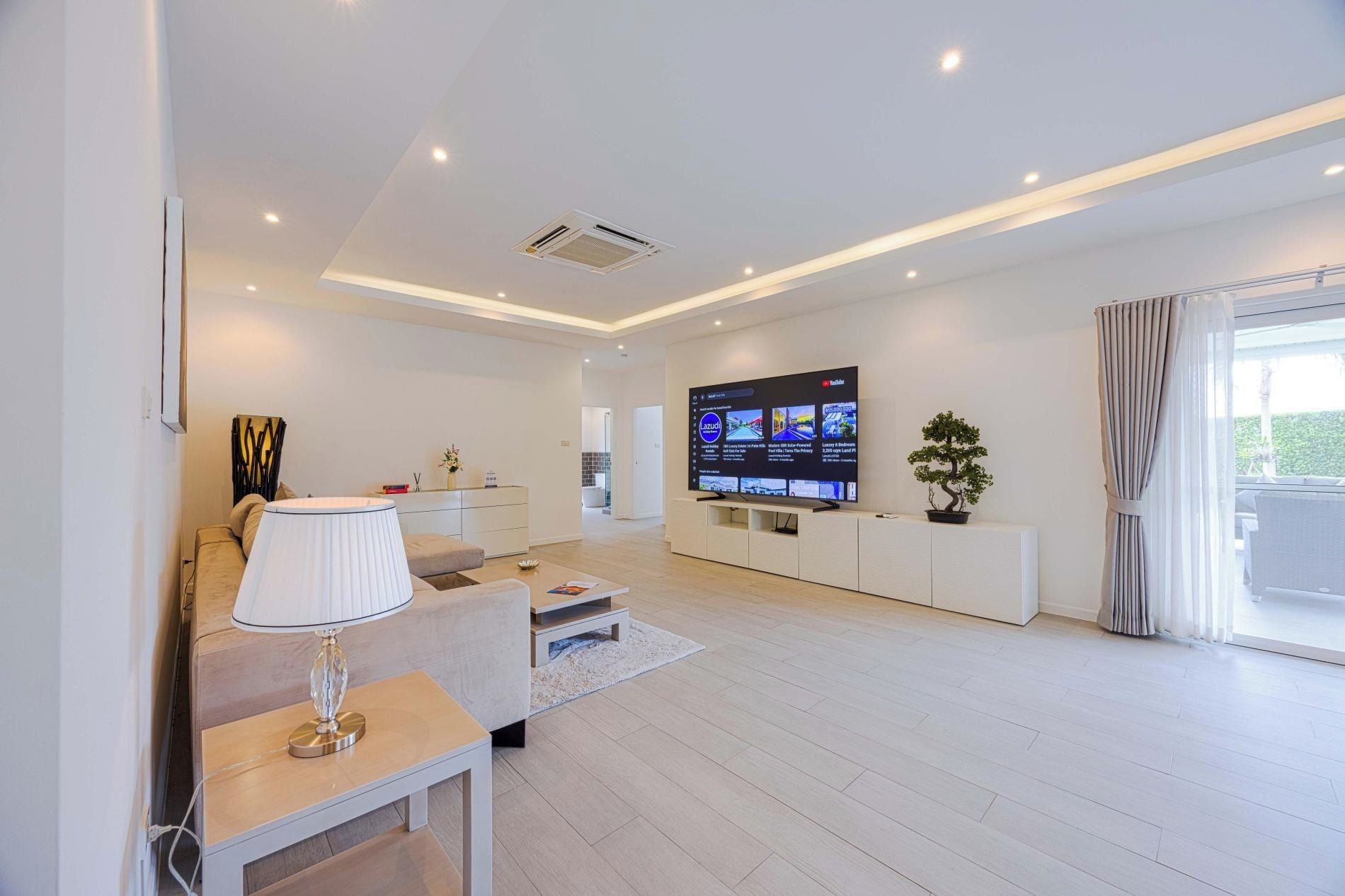 Una sala de estar moderna con televisor de pantalla plana, un sofá, una mesa de centro y una planta en maceta.