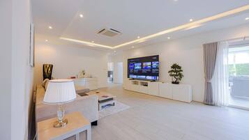 Una sala de estar moderna con televisor de pantalla plana, un sofá, una mesa de centro y una planta en maceta.