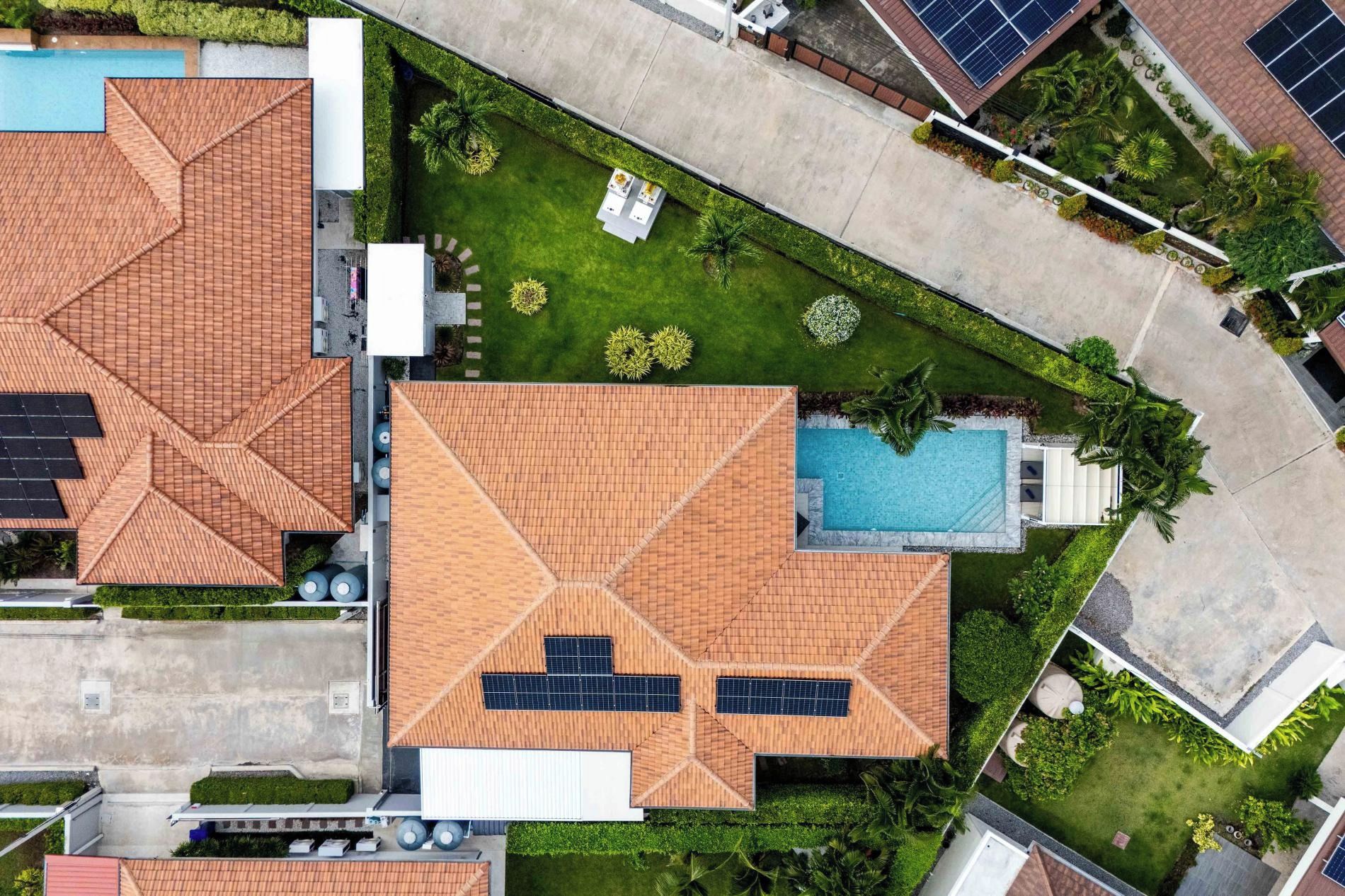 Um imóvel residencial com piscina, painéis solares e um jardim bem cuidado.