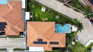 Um imóvel residencial com piscina, painéis solares e um jardim bem cuidado.