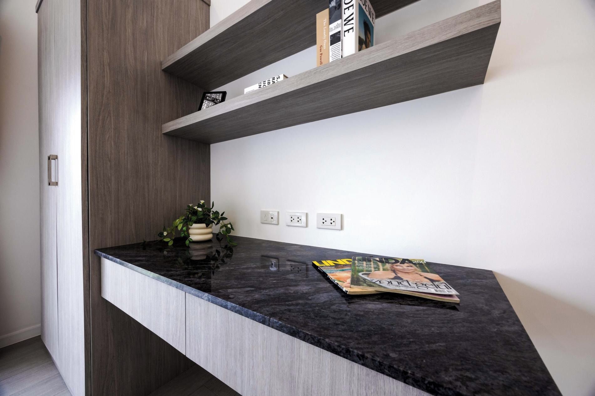 Una cocina con encimera negra, una planta en maceta y una revista.