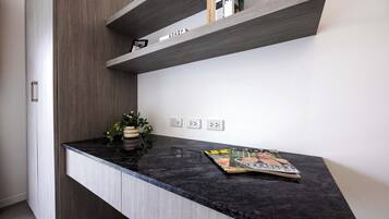 Una cocina con encimera negra, una planta en maceta y una revista.