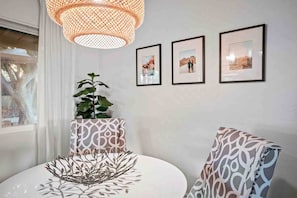 A room with a round table, a potted plant, a patterned chair, and three framed pictures on the wall. - Arcadia Retreat | Office, Fast WiFi, Fire Pit (Phoenix)