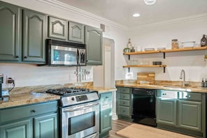 A kitchen with a stove, microwave, and dishwasher, featuring green cabinetry and granite countertops. - Arcadia Retreat | Office, Fast WiFi, Fire Pit (Phoenix)