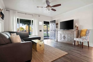 A modern living room with a sofa, a television, a patterned armchair, and a ceiling fan. - Arcadia Retreat | Office, Fast WiFi, Fire Pit (Phoenix)