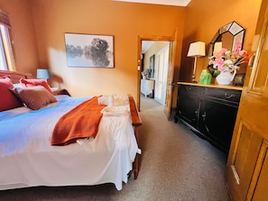 A hotel room with a bed, bedside table, dresser, and a painting on the wall. - Vineyard Charm House | McLaren Vale Retreat (Blewitt Springs)