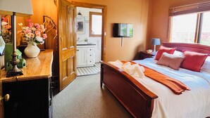 Un dormitorio con una cama, ventilador de techo, televisor y cómoda de madera.