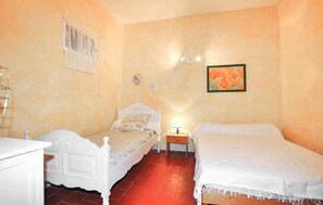 Ein Schlafzimmer mit zwei Betten, einem Nachttisch, einer Wanduhr und einem gerahmten Bild.