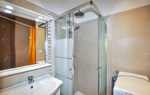 A modern bathroom with a glass-enclosed shower, a white sink, and a mirror above it. - Cozy home in Feuilla with WiFi (Feuilla)