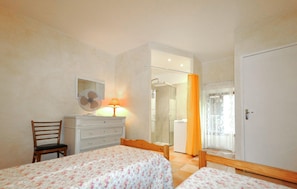 A bedroom with two beds, a dresser, a chair, a mirror, a lamp, and a shower area. - Cozy home in Feuilla with WiFi (Feuilla)
